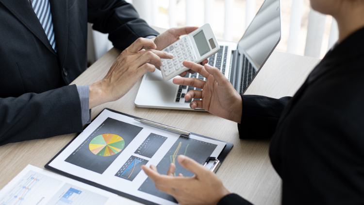 Two advisers reviewing financial charts with a calculator, illustrating how the MLI changes tax treaties